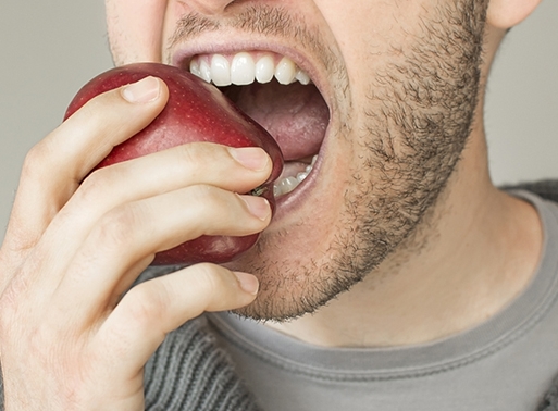 Изжога и горечь во рту. Человек кусает яблоко. Человек ест яблоко. Крепкие зубы.